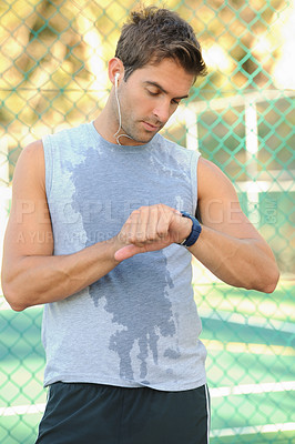 Buy stock photo Sweaty young athlete standing and checking his watch