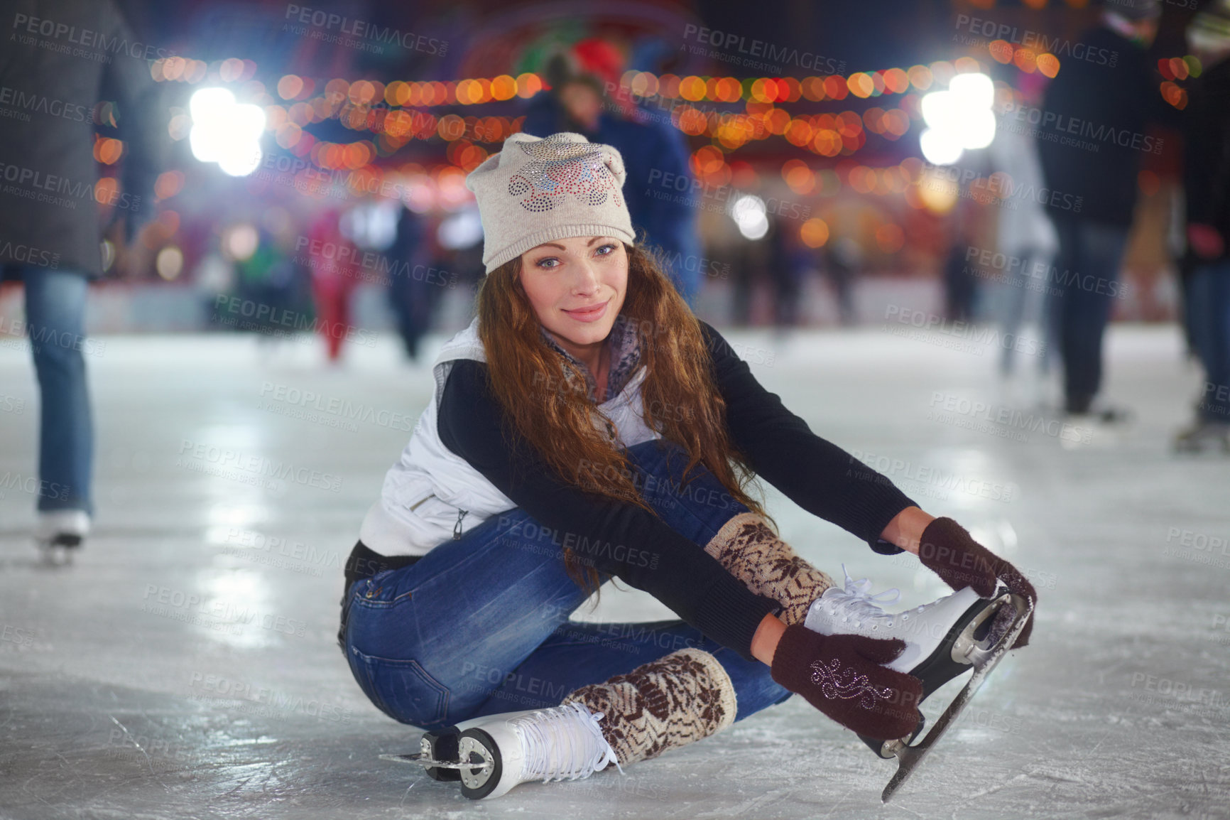 Buy stock photo Portrait of an attractive young woman sitting on an ice rink stretching her arms
