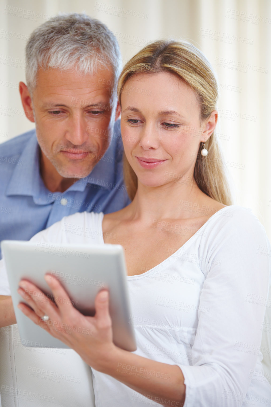 Buy stock photo A married couple sharing a digital tablet at home