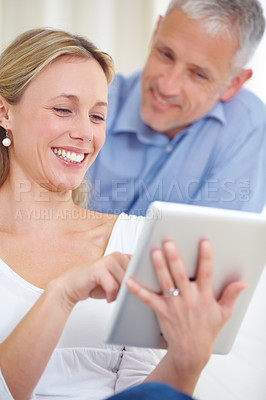 Buy stock photo An attractive young woman using her digital tablet with her husband standing behind her