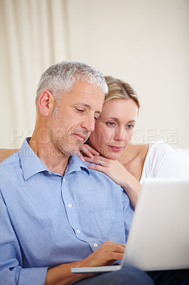 Buy stock photo A married couple sitting with their laptop at home