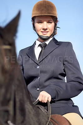 Buy stock photo Low angle portrait of a young woman sitting on her horse