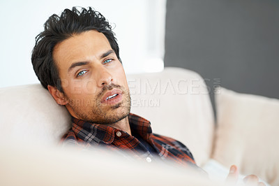 Buy stock photo Man, portrait and serious on sofa for relax, peace and calm expression in living room of apartment or home. Person, face and confidence or pride on couch in lounge for chill, rest or shirt on weekend
