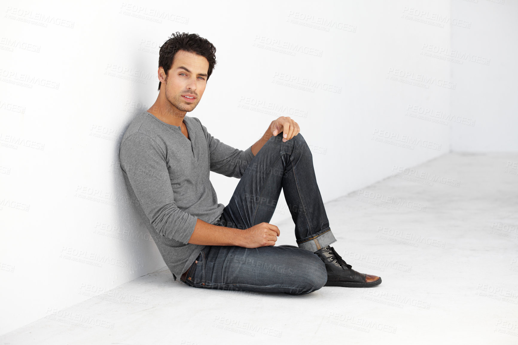 Buy stock photo Serious, fashion and portrait of young man by white wall with casual, stylish and trendy outfit. Attractive, confidence and handsome male model from Canada sitting on floor with edgy and cool style.