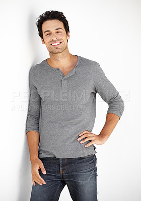 Buy stock photo Portrait of a handsome young man leaning against a wall with his hand on his hip