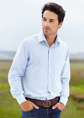 Buy stock photo A handsome young model standing outside with his hands in his pockets
