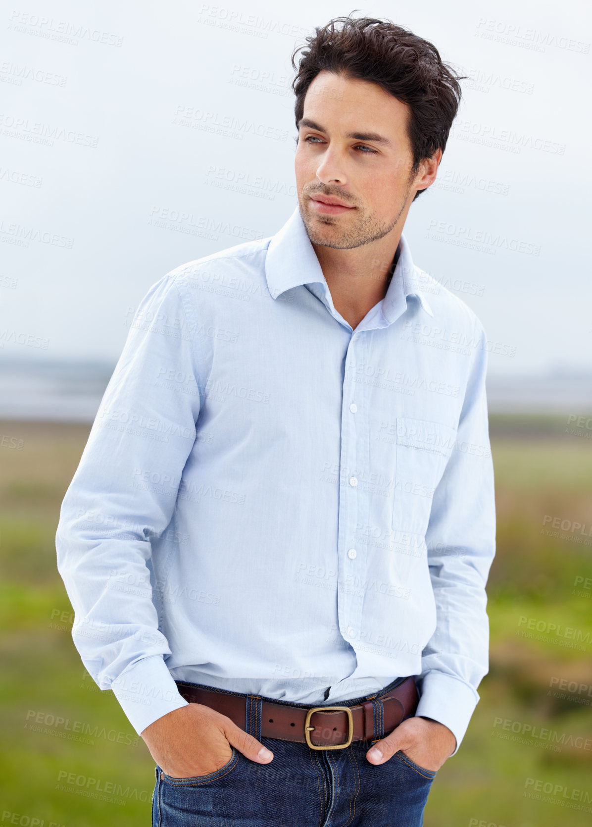 Buy stock photo A handsome young model standing outside with his hands in his pockets