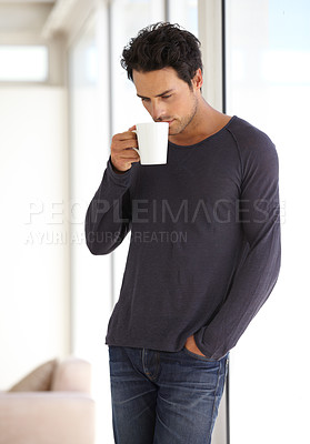 Buy stock photo A handsome young man sipping his morning coffee