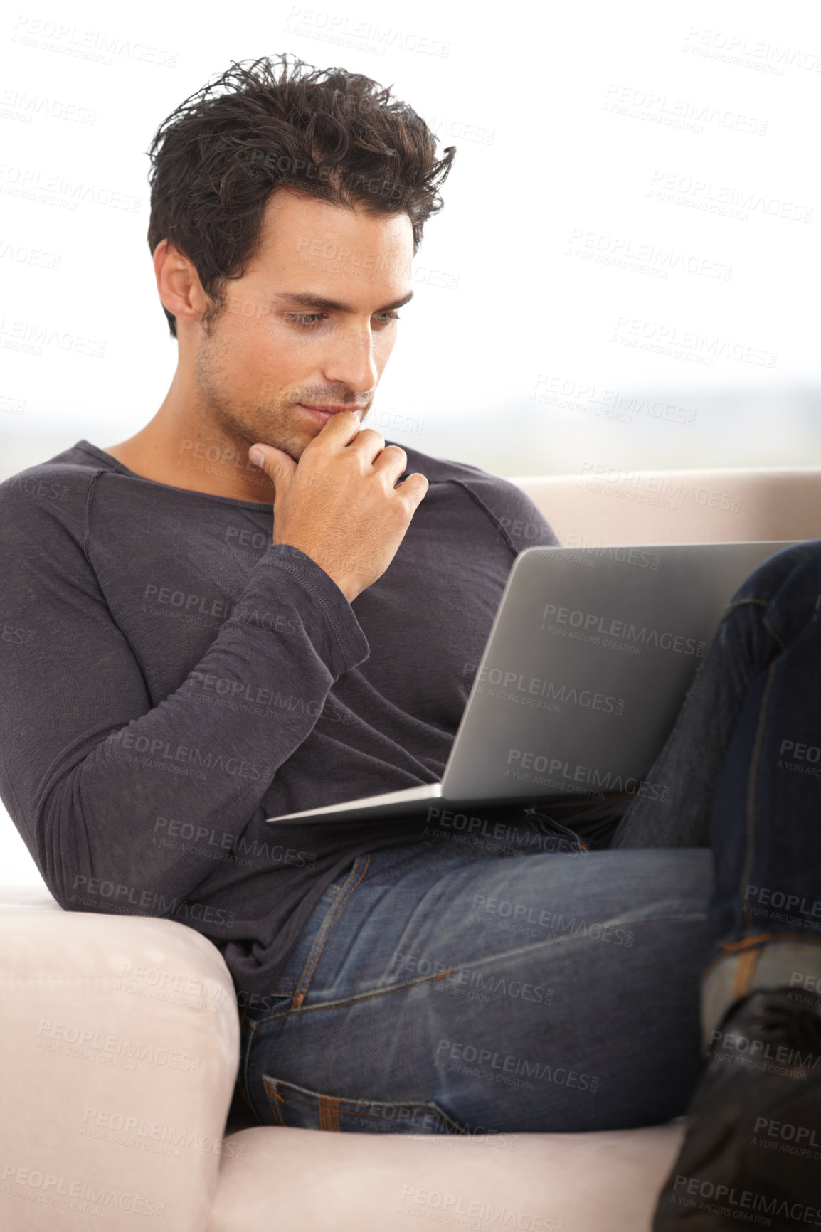 Buy stock photo A handsome young man thinking while working on his laptop