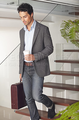 Buy stock photo A handsome young businessman walking to work with his briefcase and a coffee