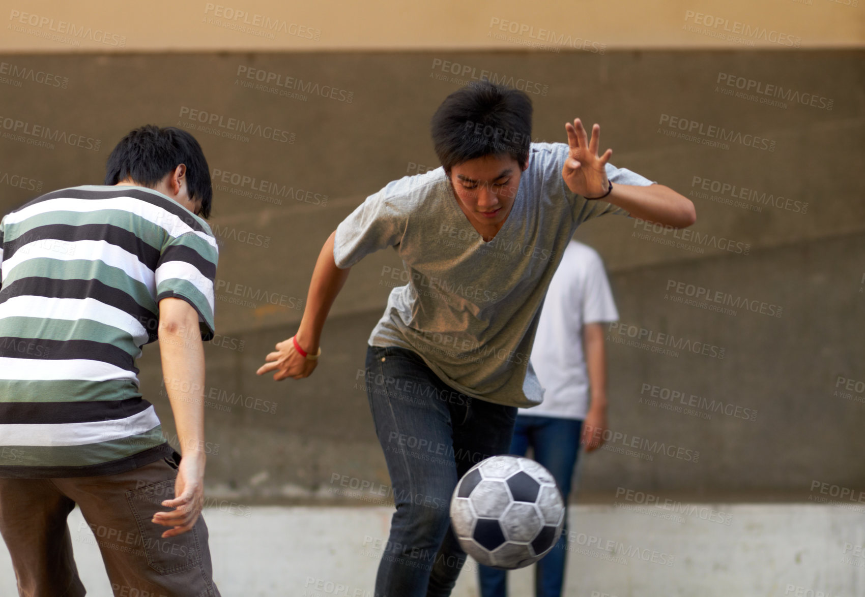 Buy stock photo Young asian males playing soccer outside