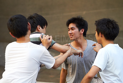 Buy stock photo Asian teen shoving his friend while another tries to break up the fight