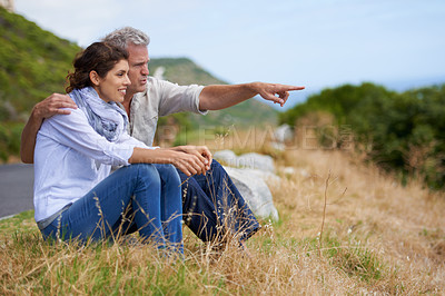 Buy stock photo Mature, couple and pointing at nature on holiday, vacation or embrace with love or support in retirement. Happy, man and woman together sightseeing on hill, mountain or relax in environment adventure