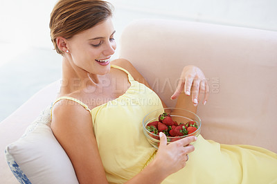 Buy stock photo Pregnant woman, eating strawberries and happy in home, alone and enjoying delicious pregnancy craving. Good mood, fruit and maternity wellness with healthy food snack and nutrition satisfaction
