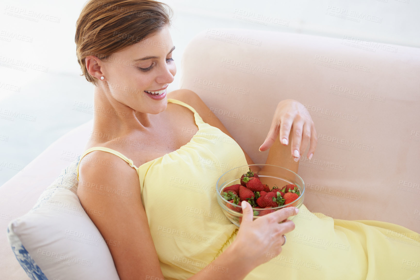 Buy stock photo Pregnant woman, eating strawberries and happy in home, alone and enjoying delicious pregnancy craving. Good mood, fruit and maternity wellness with healthy food snack and nutrition satisfaction
