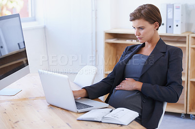 Buy stock photo A pregnant businesswoman working on a laptop at her office desk