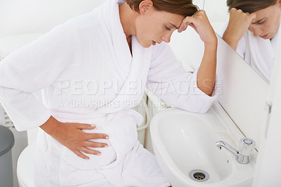 Buy stock photo A pregnant woman struggling with morning sickness in the bathroom