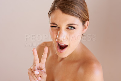 Buy stock photo Studio portrait of a young women winking and giving the 'peace' sign to the camera