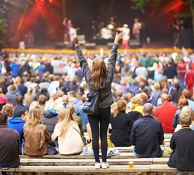 Buy stock photo Rear-view shot of a crowd at an outdoor music festival with the focus on a female fan cheering