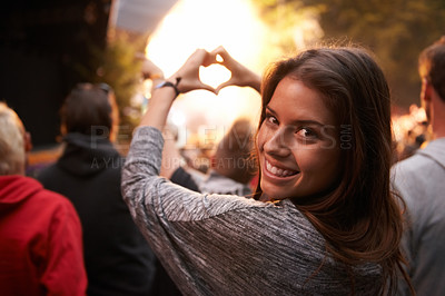 Buy stock photo Portrait, heart and hand gesture with a woman at a concert as part of the crowd or audience of a festival. Face, party and smile with a happy young female person outdoor at a music performance event