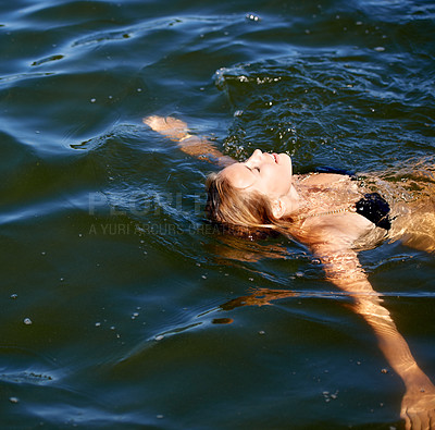 Buy stock photo Shot of an attractive young woman floating on her back in a lake