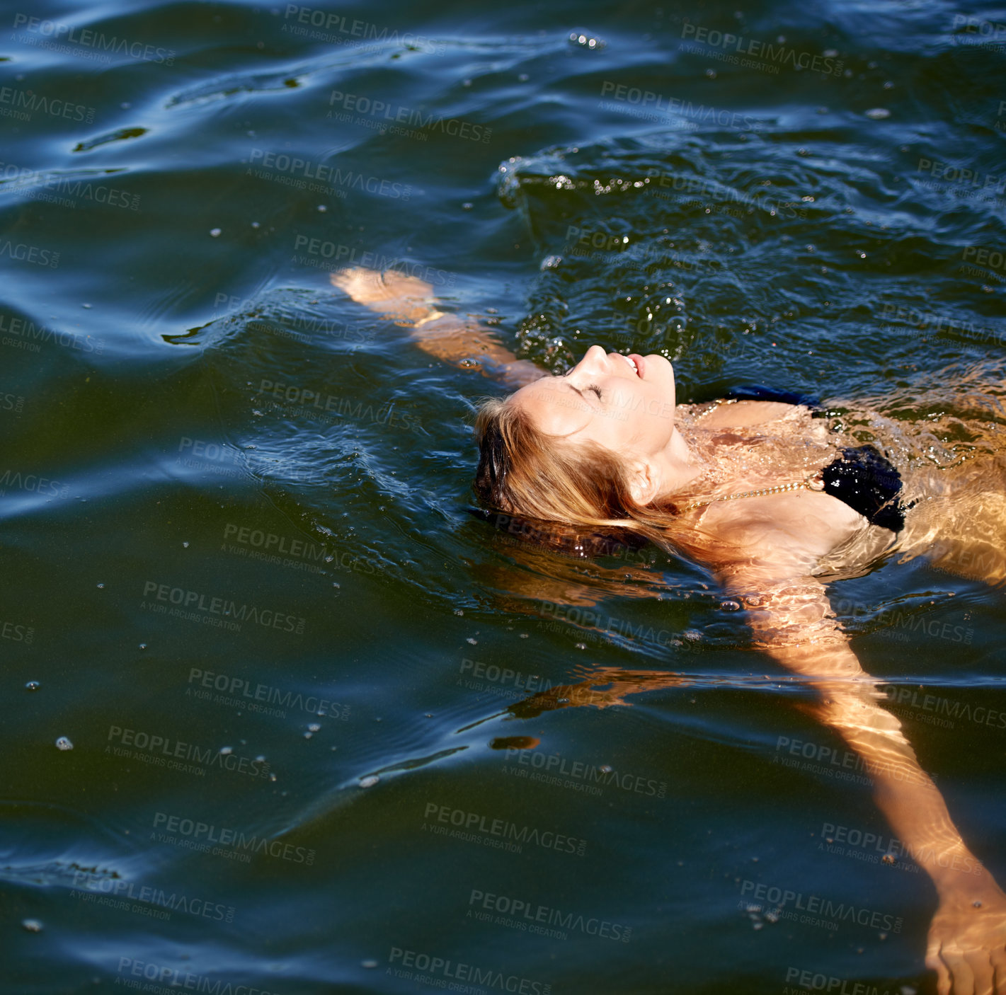 Buy stock photo Shot of an attractive young woman floating on her back in a lake