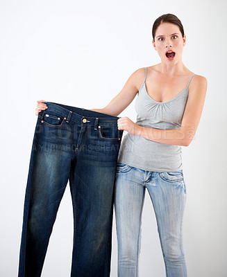 Buy stock photo Diet, weight loss and woman with surprise from jeans, change in size or white background in studio. Shocked, portrait or person with crazy reaction to transformation in fitness or large denim pants