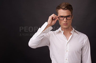 Buy stock photo A handsome young man putting on his glasses