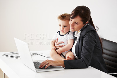 Buy stock photo Working mom talking on the phone while holding a baby and typing on her laptop