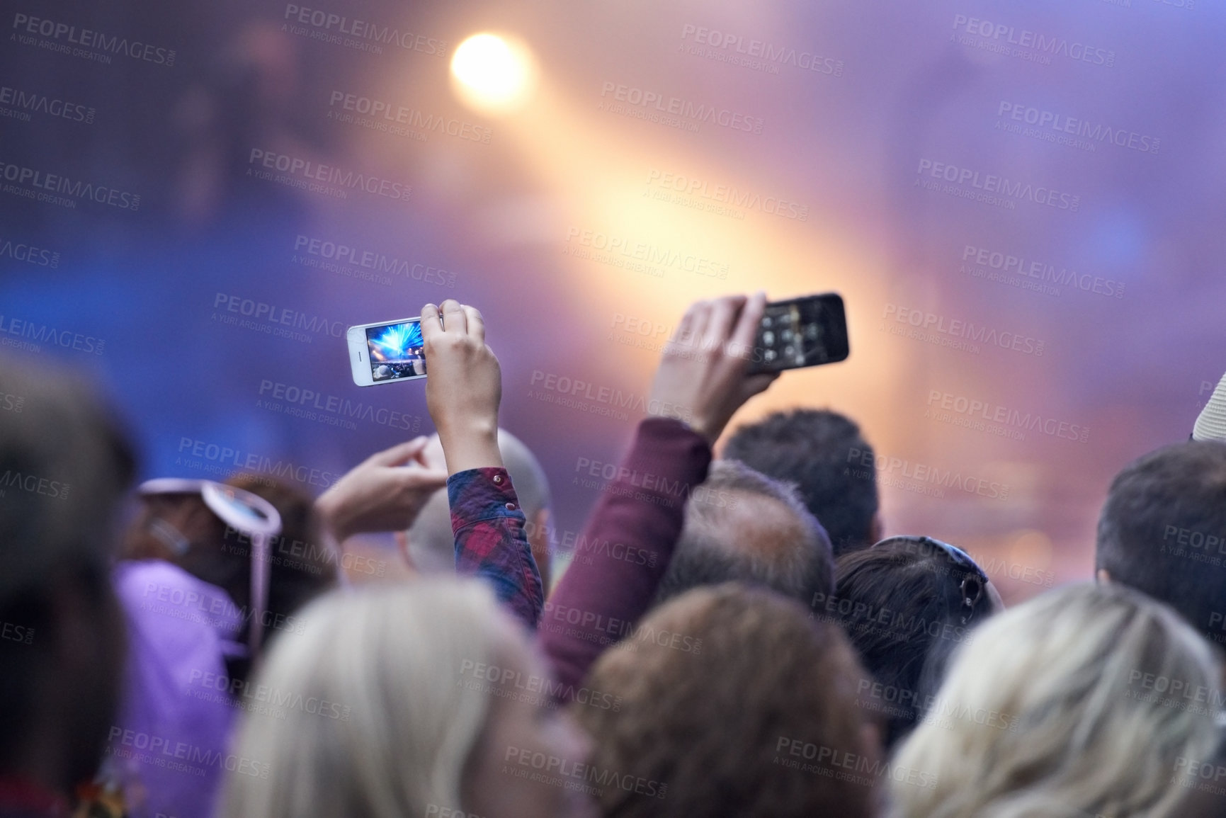 Buy stock photo Rearview shot of a crowd at a music festival with two people holding up their camera phones