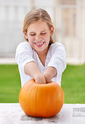 Buy stock photo A little girl hollowing out a pumpkin for halloween