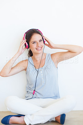 Buy stock photo Music, portrait and woman on a floor with headphones in studio, happy and streaming on a wall background. Face, smile and girl relax with podcast, radio or audio track while sitting against mockup