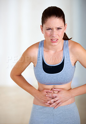 Buy stock photo Portrait of an attractive young woman holding her stomach in pain