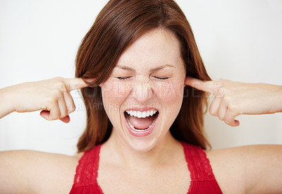 Buy stock photo An attractive young woman blocking her ears and schouting