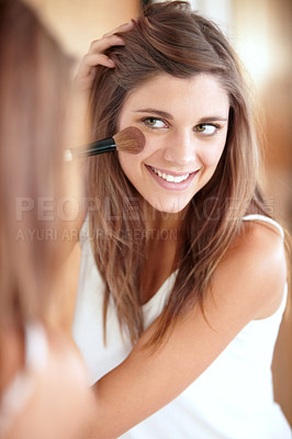 Buy stock photo An attractive young woman applying blush