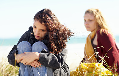 Buy stock photo Sisters, outdoor and women on the ground, angry and stress with depression, disagreement and anxiety. Female people, girls and siblings outside, beach and mental health issue with argument and ignore