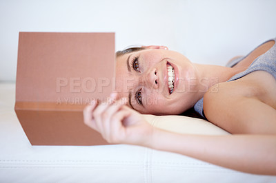 Buy stock photo Book, smile and a woman reading on a sofa in the living room of her home on the weekend for leisure. Relax, novel or literature with a happy young person in her apartment for a storytelling hobby