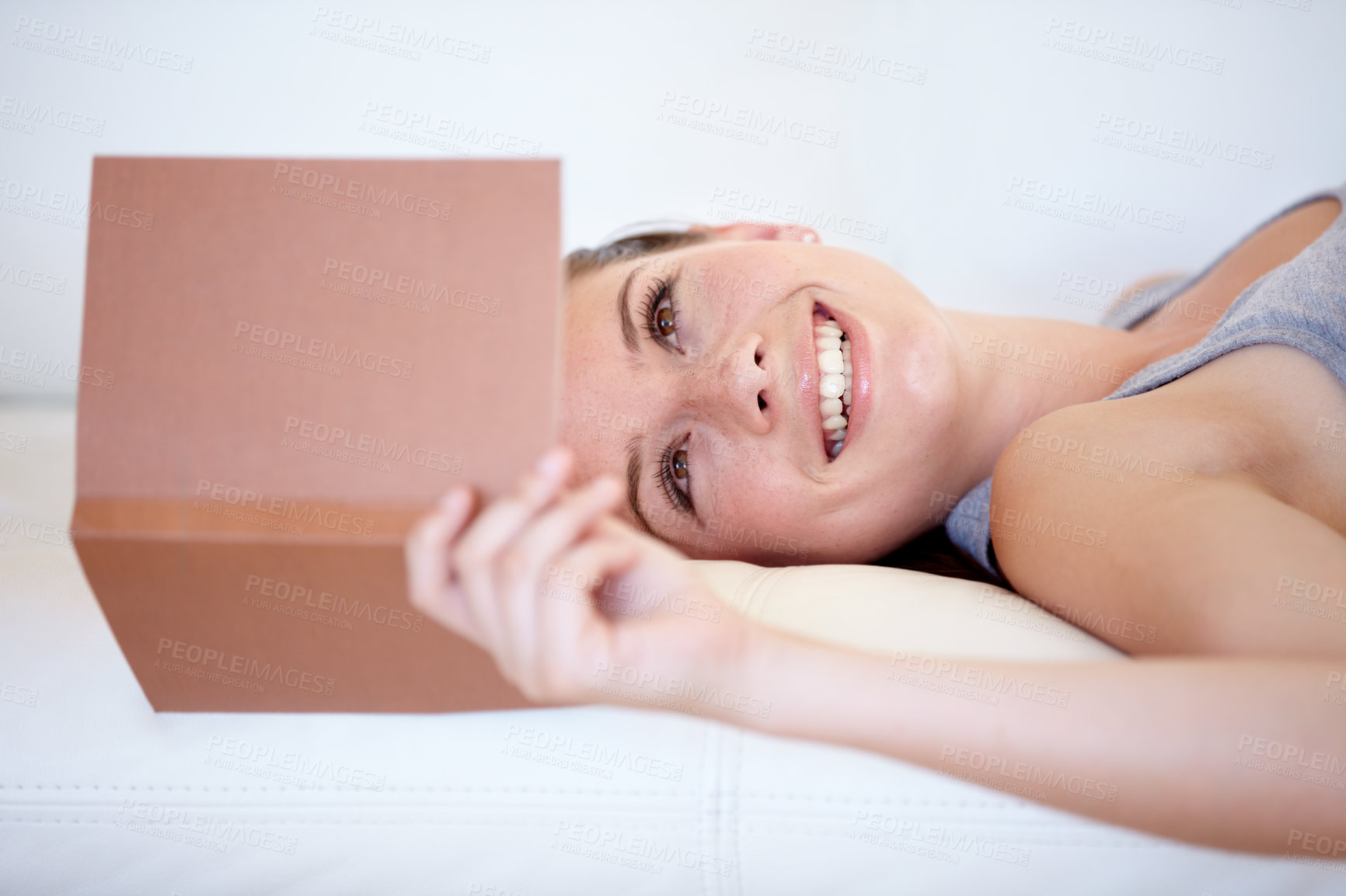 Buy stock photo Book, smile and a woman reading on a sofa in the living room of her home on the weekend for leisure. Relax, novel or literature with a happy young person in her apartment for a storytelling hobby