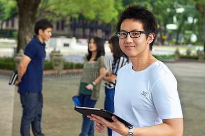 Buy stock photo Portrait of a handsome young student working on his digital tablet outside