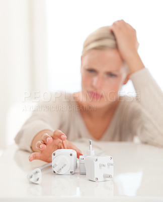 Buy stock photo Shot of a young woman reaching for power connection plugs