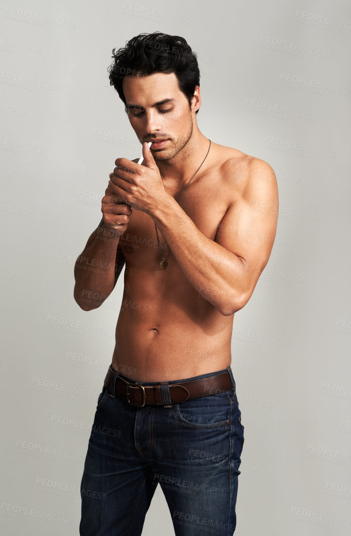 Buy stock photo Shirtless, cigarette and man smoking in a studio for grungy, cool and attractive personality. Confidence, smoke and young male model from Canada with tobacco in jeans isolated by gray background.