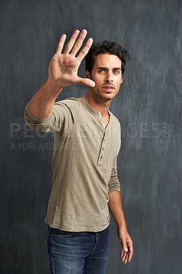 Buy stock photo Serious, hand and portrait of man with stop for no, wait or rejection expression by wall. Upset, scared and young male person from Canada with casual style and fear palm gesture by gray background.