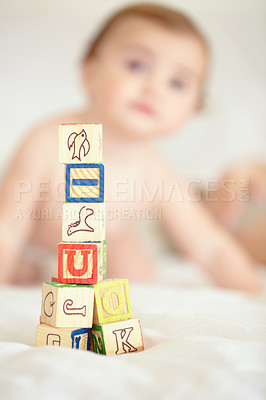 Buy stock photo A tower of building blocks in the foreground with a cute baby sitting in the background
