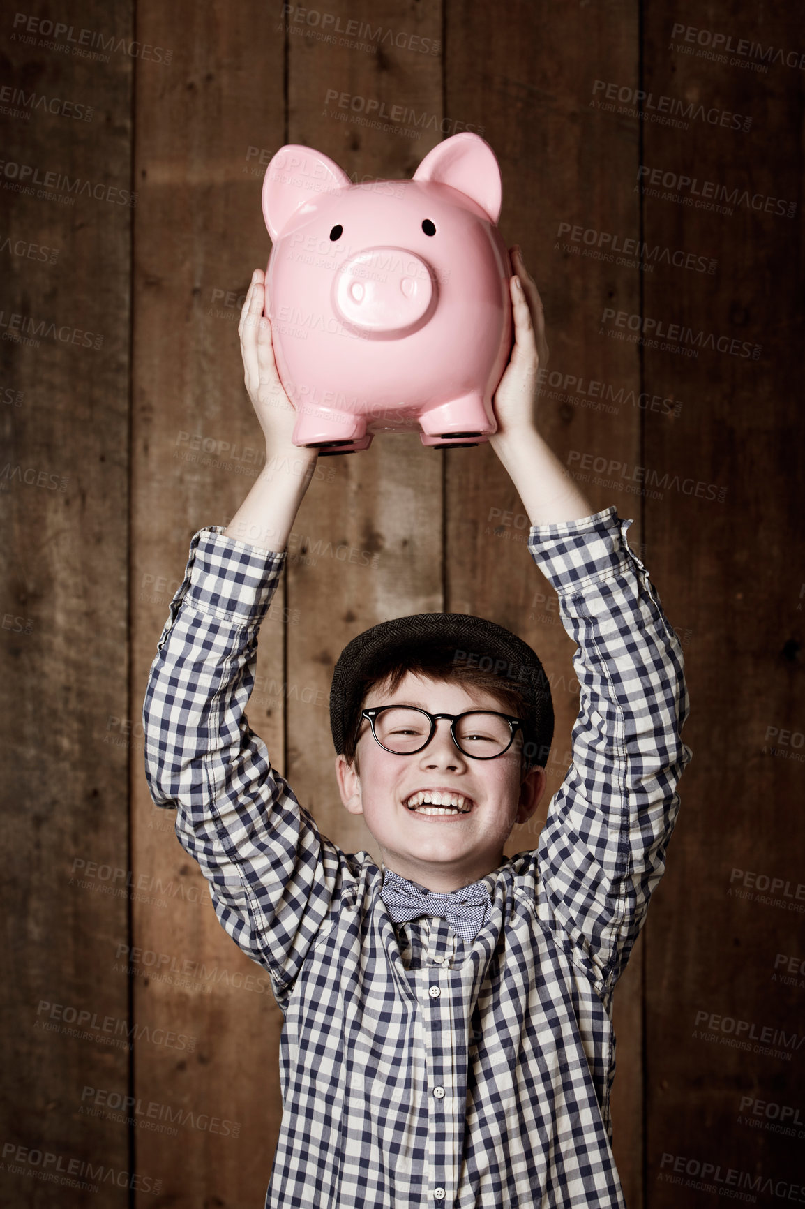 Buy stock photo Young child, piggy bank and happy in portrait in studio, money saving and cash savings in youth with retro fashion. Boy, smile and face for coin banking and safe for bills with glasses by backdrop