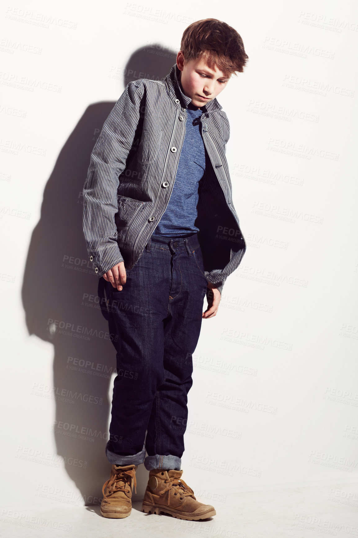 Buy stock photo Young adolescent boy looking insecure and shy against a white background