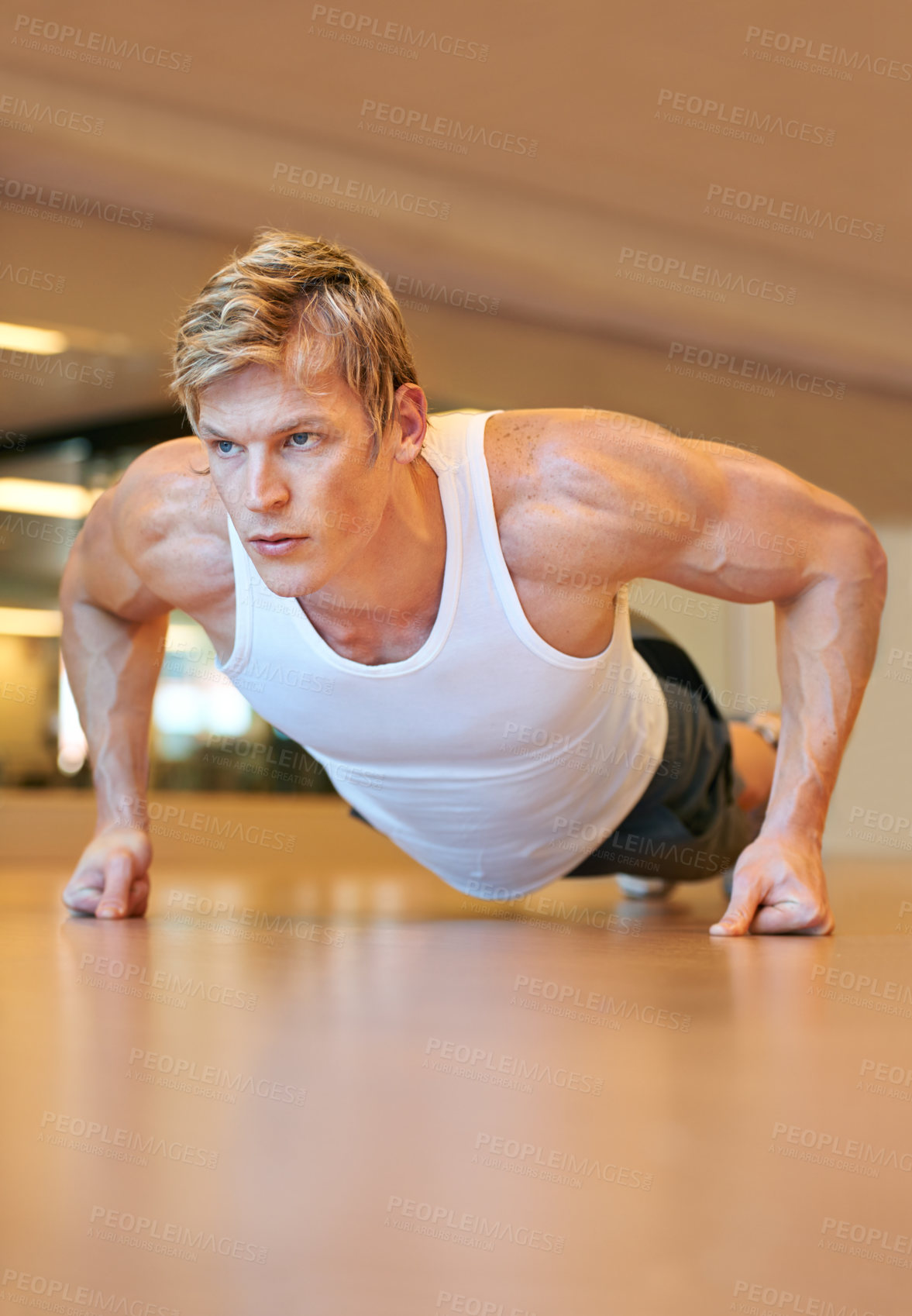 Buy stock photo Fit young man doing push ups in a health club
