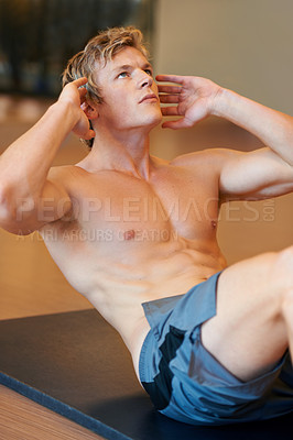 Buy stock photo Fit young guy doing sit ups on a mat at the gym