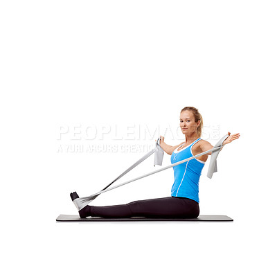 Buy stock photo A young blonde woman sitting on a mat and exercising with a resistance band - portrait