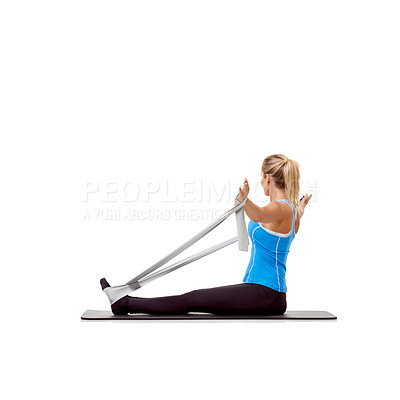 Buy stock photo A young blonde woman sitting on a mat and exercising with a resistance band - rear-view
