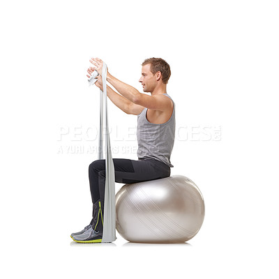 Buy stock photo A young man sitting on a Swiss ball and pulling a resistance band